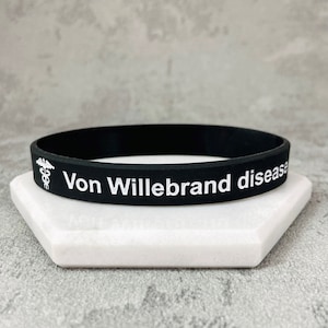 May include: Black silicone wristband with white text that reads "Von Willebrand disease" and a white medical symbol.