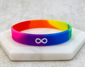 Könnte beinhalten: Regenbogen-Silikonarmband mit einem weißen Unendlichkeitszeichen.