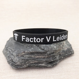 May include: Black silicone bracelet with white text that reads "Factor V Leiden" and a medical symbol.