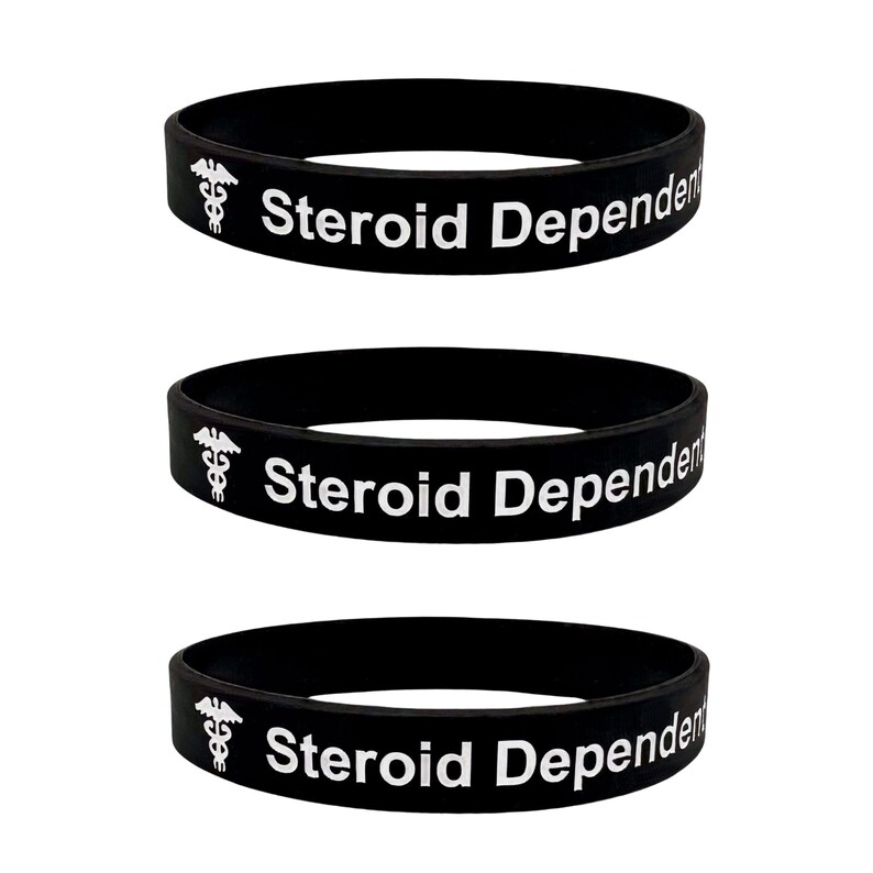 Peut inclure: Trois bracelets en silicone noir avec le texte "Steroid Dependent" et un symbole de caduc&eacute;e blanc.