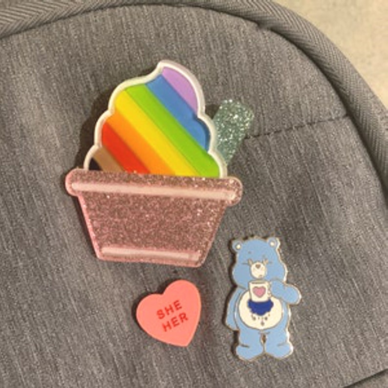 Pronoun pin attached to a backpack demonstrating everyday use as an accessory