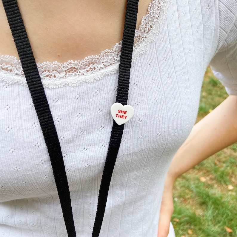 Person wearing a lanyard with a pronoun pin attached, showing how the badge looks when worn