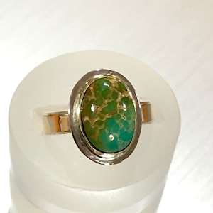 May include: A silver ring with an oval-shaped green turquoise stone set in a silver bezel.