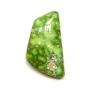 May include: A green and white cabochon gemstone with a marbled pattern. The stone is cut in a freeform shape.