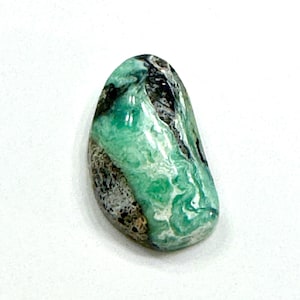 May include: A green and black cabochon gemstone with a swirling pattern.