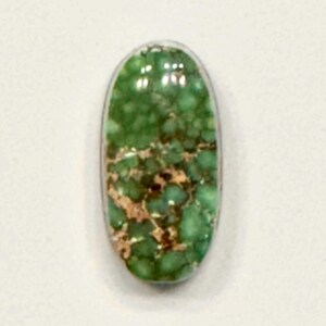 May include: A green and brown oval cabochon gemstone with a marbled pattern.