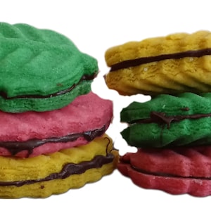 May include: A stack of four leaf-shaped cookies with chocolate filling. The cookies are green, pink, yellow, and green.