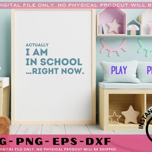 May include: A white sign with the text "Actually I am in school...right now." in blue text. The sign is in a room with a wooden table, a teddy bear, and a shelf with pink and blue decorations.