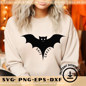 Puede incluir: Una sudadera crema con un diseño de murciélago negro y las palabras "SHIT CRAZY". La imagen también incluye el texto "SVG- PNG-EPS-DXF" y un icono de "DESCARGA INSTANTÁNEA".