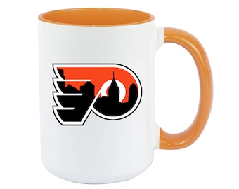 May include: White ceramic mug with an orange rim and handle. The mug features a black and orange Philadelphia Flyers logo with a silhouette of the Philadelphia skyline.