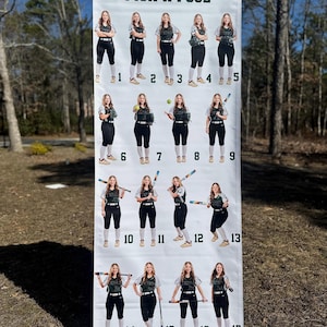 Op de afbeelding: Een groot spandoek met de tekst "PICK A POSE" toont 17 afbeeldingen van een softbalspeler in verschillende poses. De speler draagt een groen en wit softbaluniform met een zwarte broek en witte sokken. De banner is buiten.