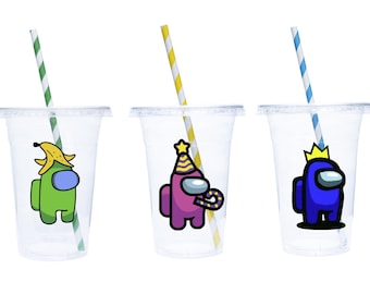 Puede incluir: Tres vasos de plástico transparentes con pajitas y diseños coloridos de personajes de Among Us. Los personajes llevan una banana, un gorro de fiesta y una corona.