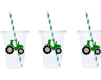 May include: Three clear plastic cups with green and white striped straws. Each cup has a green tractor sticker with black wheels.