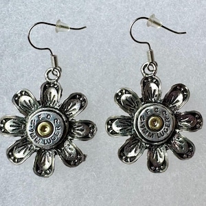 May include: A pair of silver flower-shaped earrings with a 9mm Luger bullet casing in the center of each flower.
