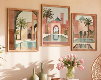 May include: Three framed wall art prints depicting architectural scenes with palm trees, arched doorways, and pools in shades of terracotta, peach, and green. The prints are displayed in light wood frames on a wall above a wooden console table.