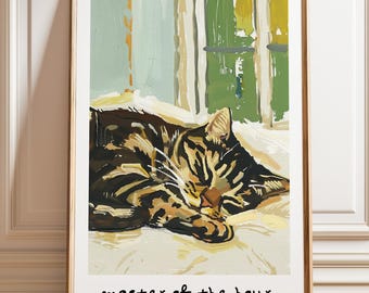 May include: A framed art print featuring a painting of a brown and black tabby cat sleeping on a white surface. The background shows green and light blue vertical panels. The text "master of the hour." is printed in black at the bottom of the print.