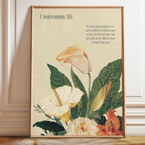 Può includere: Una stampa artistica incorniciata su sfondo beige chiaro con un'illustrazione botanica di vari fiori e foglie verdi. Il testo recita Deuteronomy 31:6 e include il versetto: Be strong and courageous. Do not be afraid or terrified because of them, for the Lord your God goes with you; he will never leave you nor forsake you.
