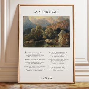 以下が含まれることがあります： 上部に「Amazing Grace」のタイトル、中央に山、木々、川の風景画、そしてジョン・ニュートンによる賛美歌の全歌詞が白い背景に黒い文字で印刷された、額装されたウォールアートプリント。