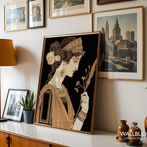 May include: A framed art print featuring a stylized illustration of a person in profile with an intricate hairstyle, wearing a patterned headband and draped garment, holding a long thin staff against a solid black background.