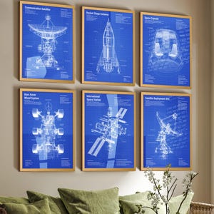 Puede incluir: Un conjunto de seis l&aacute;minas enmarcadas con diagramas t&eacute;cnicos en blanco sobre fondo azul. Las impresiones muestran un sat&eacute;lite de comunicaciones, una etapa de cohete, una c&aacute;psula espacial, un rover de Marte, una estaci&oacute;n espacial y un brazo.