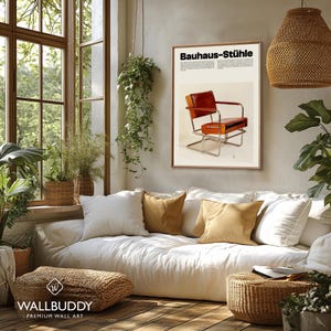May include: A rectangular wall art print titled Bauhaus-St&uuml;hle featuring a brown leather chair with a chrome frame. The poster has a cream background with black text and is displayed in a thin wooden frame on a light-colored wall above a sofa.