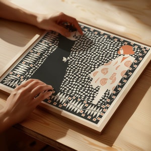 May include: A square framed art print featuring a graphic illustration of two figures against a black and white checkered background. One figure is in a solid black dress, while the other wears a cream-coloured garment with orange circular patterns.