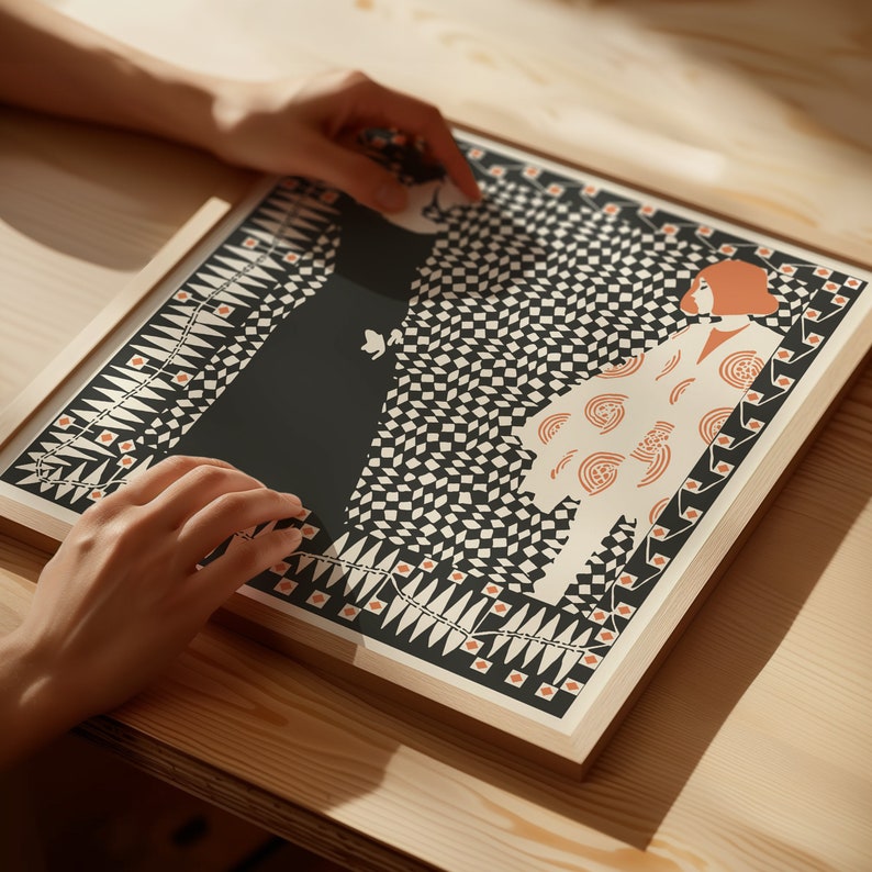 May include: A square framed art print featuring a graphic illustration of two figures against a black and white checkered background. One figure is in a solid black dress, while the other wears a cream-coloured garment with orange circular patterns.