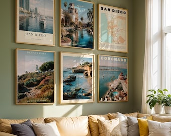 May include: A gallery wall set of six framed posters featuring San Diego landmarks including the harbor, Balboa Park, a city map, Point Loma, a coastal scene, and Coronado Island, all displayed in light wood frames on a muted green wall.