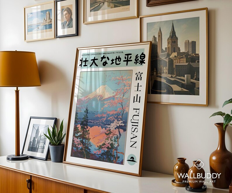 May include: A framed vertical poster featuring a stylised illustration of Mount Fuji with pink cherry blossoms, pine trees, and a reflective lake. The text reads 壮大な地平線, 富士山, and FUJISAN. The poster is displayed in a gold frame.