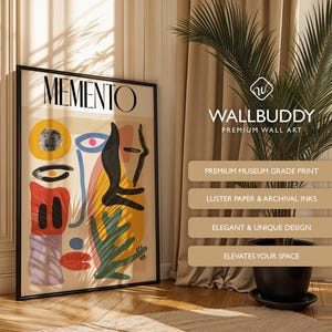 May include: A framed wall art print titled MEMENTO featuring an abstract composition of geometric shapes and organic forms in yellow, red, blue, black, and purple on a beige background, displayed in a black frame with a clean, modern aesthetic.