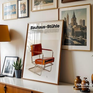 May include: A framed vertical poster titled Bauhaus-St&uuml;hle featuring a photograph of a brown leather and chrome tubular steel armchair. The poster includes descriptive German text above the chair image, displayed in a gold frame on a white wall.