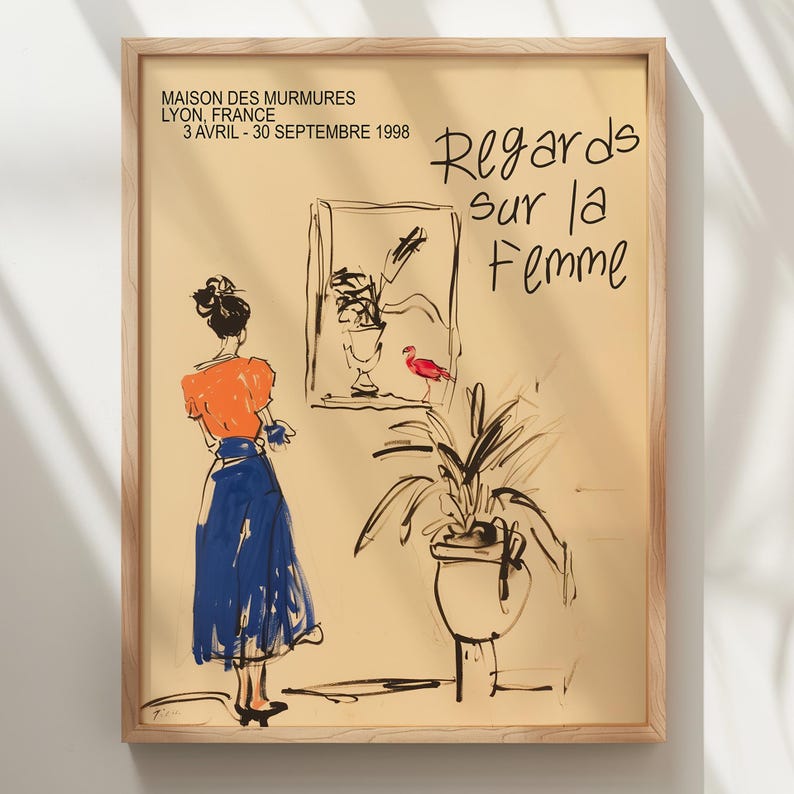Op de afbeelding: Een ingelijste poster met een gele achtergrond en zwarte lijntekeningen van een vrouw in een blauwe rok en oranje top, een plant in een pot en een rode vogel. De tekst op de poster luidt "MAISON DES MURMURES LYON, FRANKRIJK 3 APRIL - 30 SEPTEMBER 1998 Regards sur la Femme".
