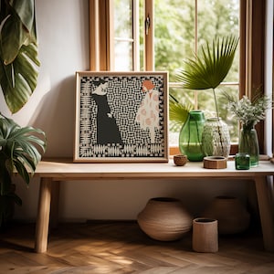 May include: A square framed print featuring a graphic illustration of two figures, one in a solid black dress and one in a patterned cream coat, set against a black and white checkered background with a decorative border of small leaves and orange squares.