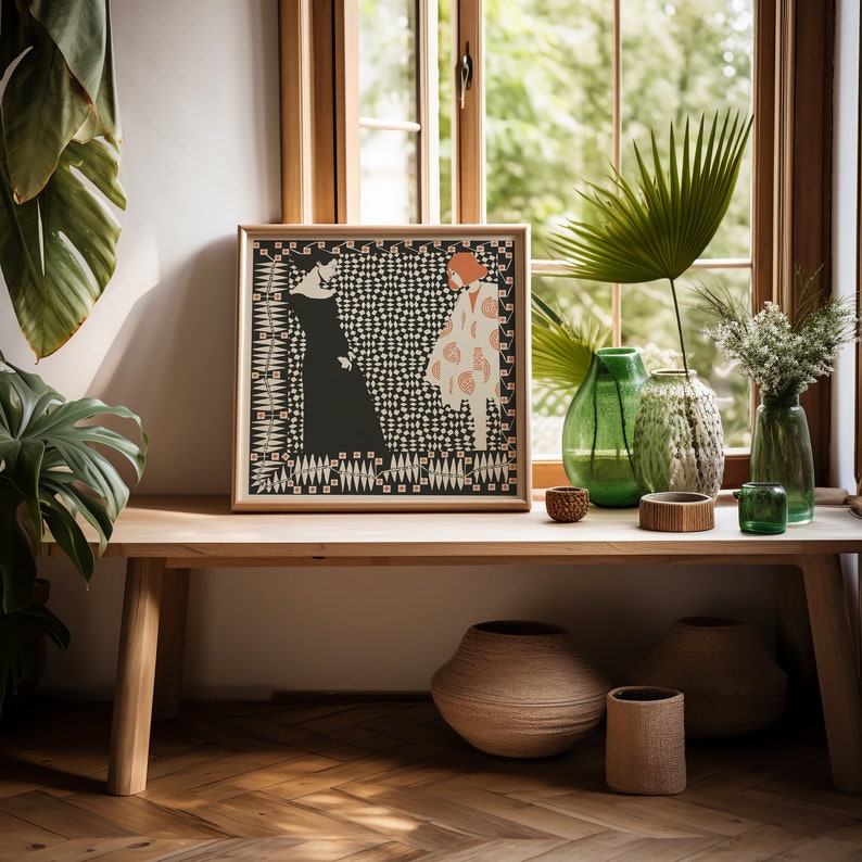 May include: A square framed print featuring a graphic illustration of two figures, one in a solid black dress and one in a patterned cream coat, set against a black and white checkered background with a decorative border of small leaves and orange squares.
