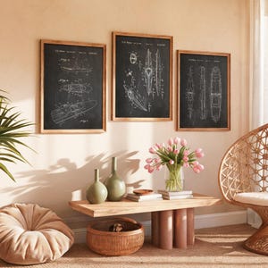 May include: Three framed wall art prints featuring white technical patent drawings of kayaks on a black background. The prints are displayed in light wood frames and hung in a row on a wall above a wooden table with vases and a woven basket.