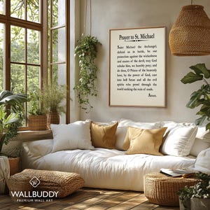 May include: A rectangular wall art print featuring the Prayer to St. Michael in black serif text on a cream background, framed in a thin wood border. The text reads: Prayer to St. Michael, Saint Michael the Archangel, defend us in battle.