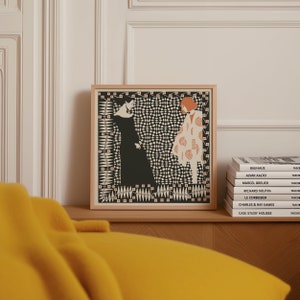 May include: A square framed art print featuring a graphic illustration of two figures. One figure wears a long black dress, while the other wears a patterned cream coat with orange accents. The background is a dense black and white geometric pattern.