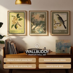 May include: Three framed vintage-style wall art prints. The prints feature botanical and wildlife themes, including a magnolia branch, egrets in a swamp, and a bird on a branch. The frames are a warm brown colour.