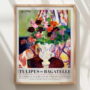 May include: A framed art print titled Tulipes de Bagatelle featuring a colorful bouquet of flowers in a white vase with blue patterns. The painting displays red, orange, and purple blooms against a draped fabric background with text at the bottom.