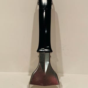 May include: A black and silver pot handle with a heat-resistant black plastic grip. The handle is designed to be attached to a pot or pan.