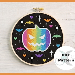 May include: A rainbow colored pumpkin with a scary face, surrounded by bats and stars on a black background. The image is in a round embroidery hoop. The text "PDF Pattern" is in a circle with a swirl design.