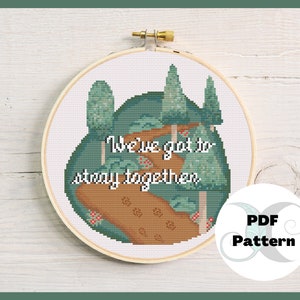 Puede incluir: Un patrón de punto de cruz que presenta un paisaje verde y marrón con árboles y el texto "We've got to stay together". El patrón está en un aro y hay un círculo blanco con el texto "PDF Pattern" en la esquina inferior derecha.