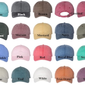 Op de afbeelding: Twintig verschillende gekleurde baseballpetten met een verweerde look. De kleuren omvatten aqua, zwart, bruin, kardinaal, bos, donkerrood, mosterd, marineblauw, olijf, periwinkle, roze, rood, koninklijk blauw, zeeschuim, steen, teal, wit, Texas oranje en wijn.