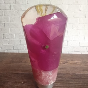 May include: A clear resin gear shift knob with a pink fabric design inside. The knob has a silver base.