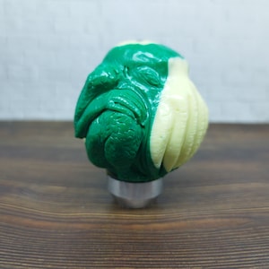 May include: Green and cream colored gear shift knob with a detailed sculpture of a creature with tentacles.