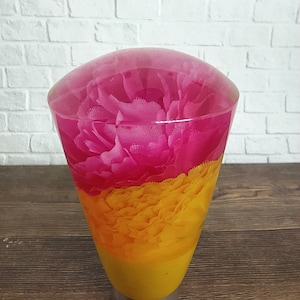 Pode incluir: Uma alavanca de câmbio de resina transparente com um design de flores rosa e amarelo. A camada superior é rosa e a camada inferior é amarela.