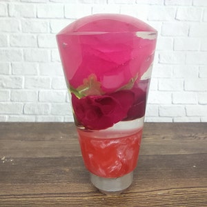 May include: A clear resin gear shift knob with pink and red roses encased inside. The roses are layered and appear to be floating in the resin.