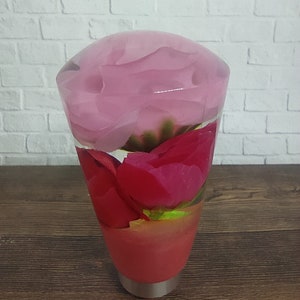 Könnte beinhalten: Ein transparenter Glas-Schalthebelknauf mit rosa und roten Rosen darin. Die Rosen sind in einem Strauß angeordnet und durch das klare Glas sichtbar.