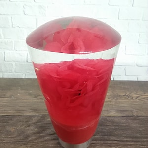 Può includere: Un pomello del cambio in vetro trasparente con un inserto in resina rossa a spirale. Il pomello ha una base in metallo argentato.