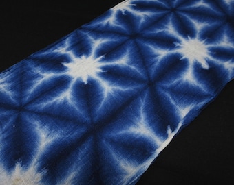 May include: Indigo blue fabric with a white starburst pattern. The textile has a diagonal orientation, with the pattern repeating across the surface. The fabric appears to be soft and lightweight, with a slightly textured appearance.